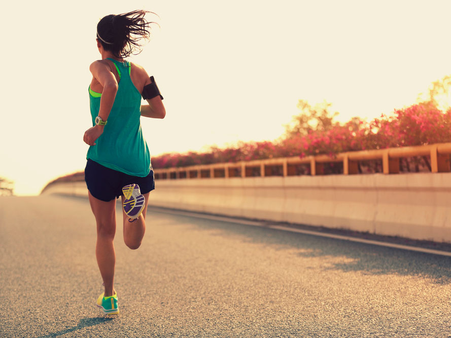 Mujer deportiva positiva en una mañana de verano trotar en la